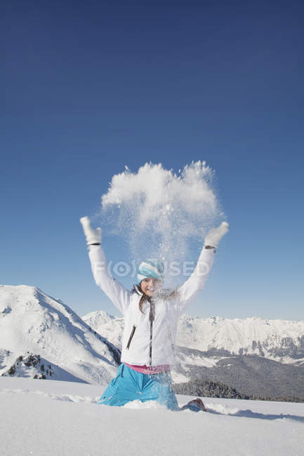 Portrait of girl in ski clothes throwing snow in air in winter mountains — Stock Photo
