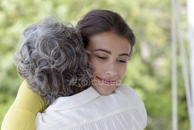 Nahaufnahme einer Mutter, die ihre erwachsene Tochter im Freien umarmt — Stockfoto