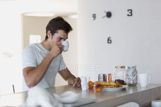 Крупним планом молодий чоловік п'є каву вдома — стокове фото