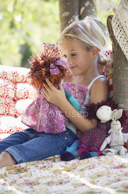 Улыбающаяся маленькая девочка с игрушками в домике на дереве — стоковое фото