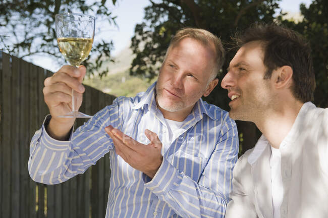Zwei Freunde blicken auf ein Weinglas — Stockfoto