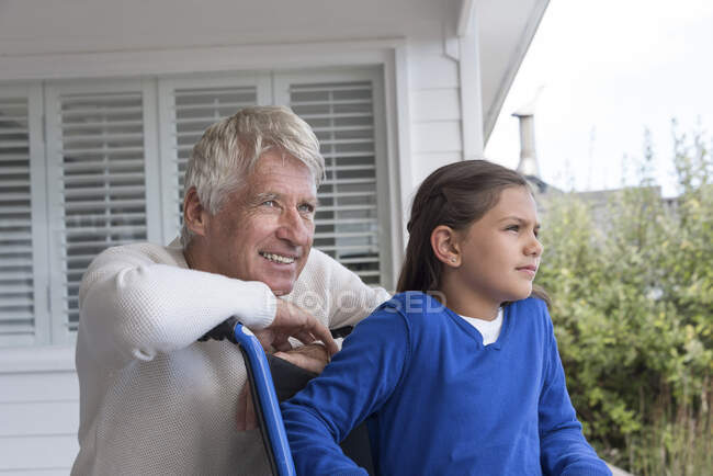 Felice uomo anziano con sua nipote in sedia a rotelle sul portico — Foto stock