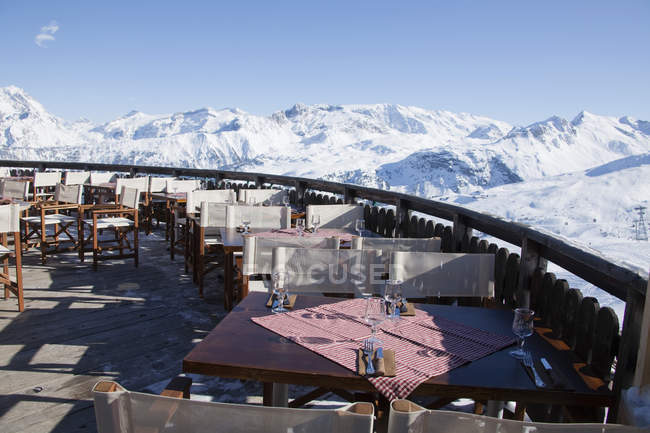 Restaurante terraza rodeada de montañas cubiertas de nieve - foto de stock