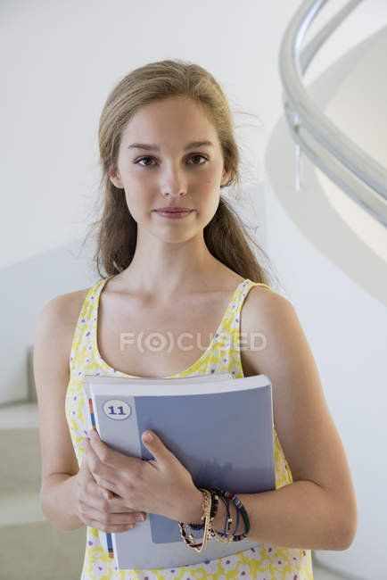 Feminino adolescente estudante segurando livros em escadas — Fotografia de Stock