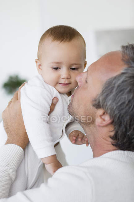 Feliz pai beijando bonito bebê filha em casa — Fotografia de Stock