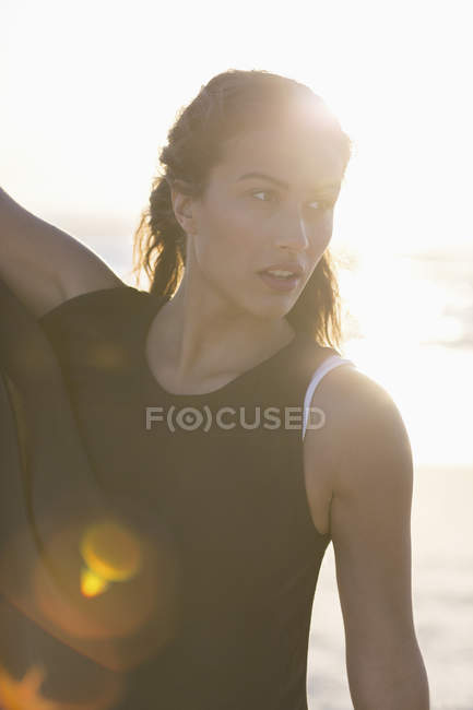 Чуттєва молода жінка позує на пляжі на сонячному світлі — стокове фото