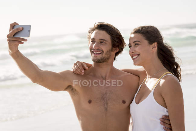 Couple prenant selfie avec téléphone portable sur la plage — Photo de stock