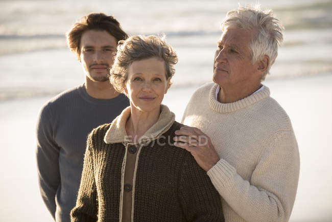 Retrato de la familia feliz de pie en la playa juntos - foto de stock