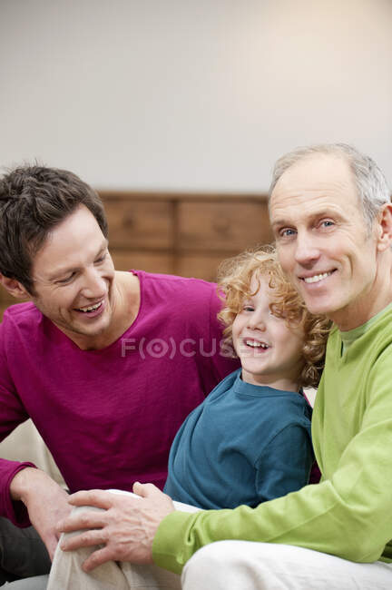 Familia sonriendo juntos en casa - foto de stock