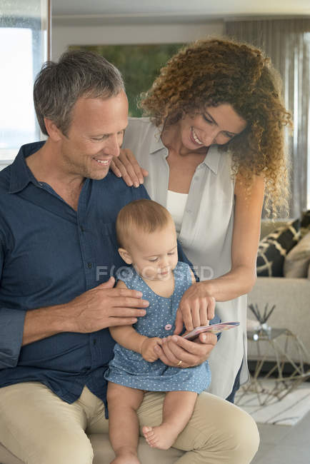Happy couple showing picture book to baby daughter — Stock Photo