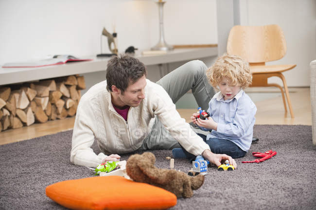 Мужчина играет с маленьким сыном на ковре дома — стоковое фото