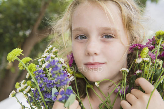 Portrait of little blonde girl holding flowers — Stock Photo