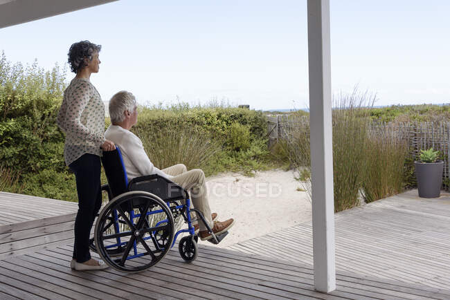Старший чоловік у інвалідному візку з дружиною на ганку — стокове фото