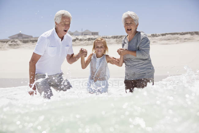 Girl having fun on sea beach with grandparents — Stock Photo