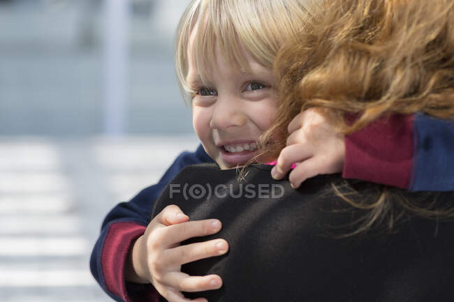 Joyeux petit garçon embrassant sa mère — Photo de stock