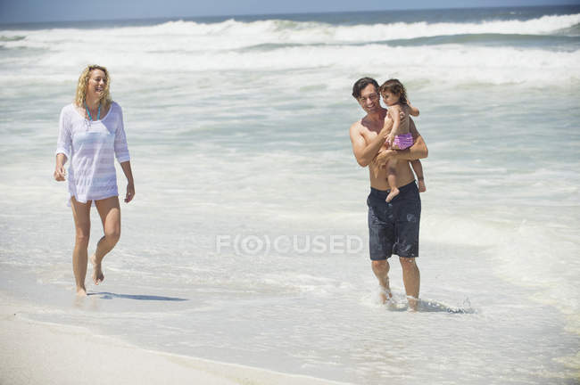 Пара прогулок по пляжу с маленькой дочерью — стоковое фото
