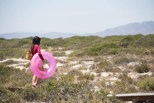 Frau mit aufblasbarem Ring läuft auf Strandpromenade an der Küste — Stockfoto