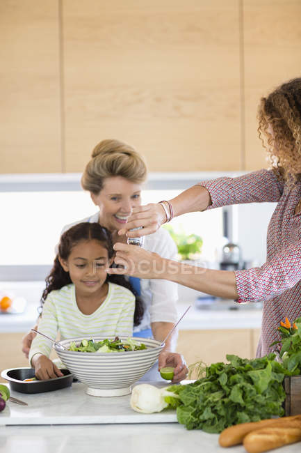 Seniorin mit Tochter und Enkelin bereitet Essen in Küche zu — Stockfoto