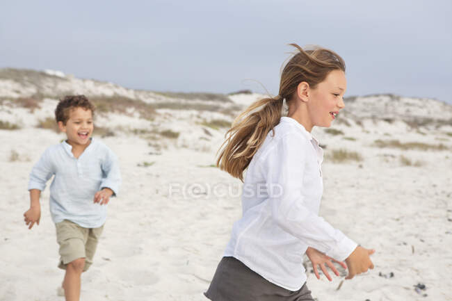 Хлопчик грає зі своєю сестрою на пляжі — стокове фото