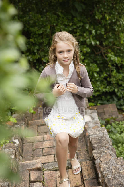 Mädchen läuft im Garten die Treppe hinauf und schaut in die Kamera — Stockfoto