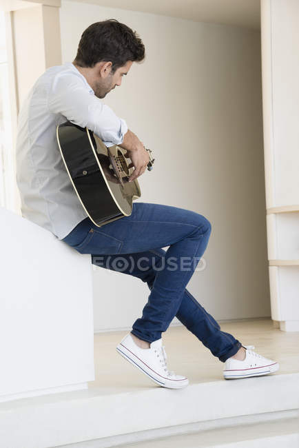 Homme détendu en chemise blanche jouant de la guitare — Photo de stock