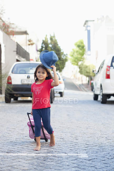Nettes kleines Mädchen läuft mit Gepäck auf der Straße — Stockfoto