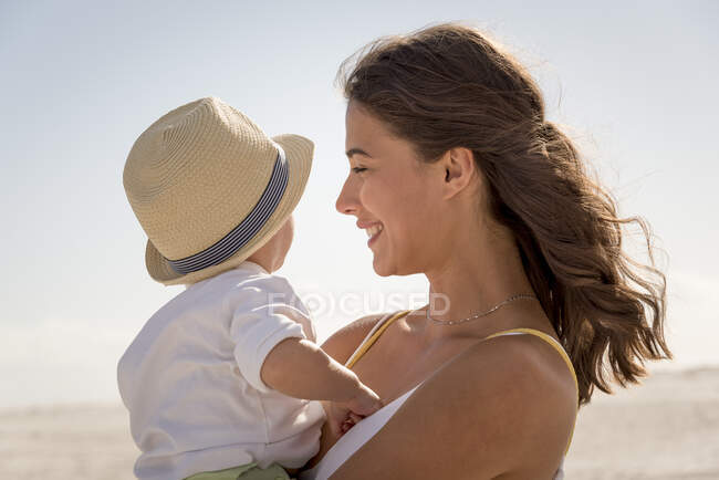Mère heureuse avec son petit fils jouissant sur la plage — Photo de stock