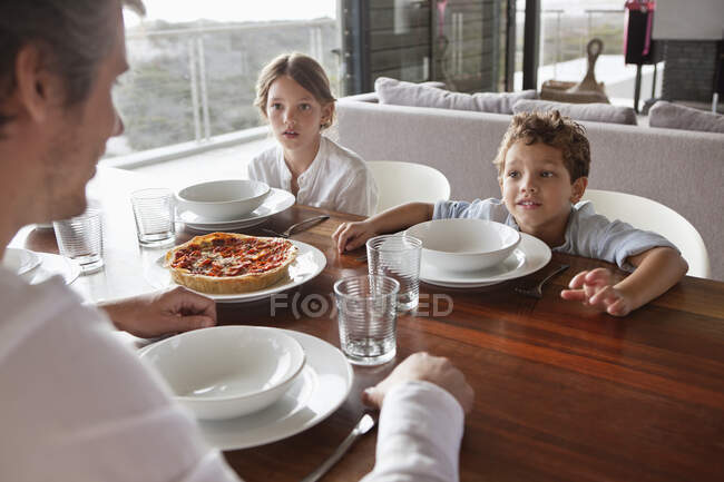 Hombre hablando con los niños durante la hora de comer - foto de stock