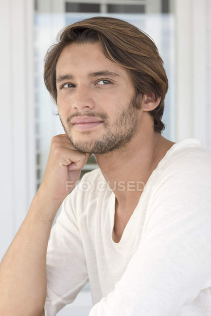 Portrait of happy young man sitting and leaning on elbow — Stock Photo
