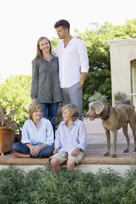 Портрет щасливої сім'ї розважається на задньому дворі з собакою — стокове фото