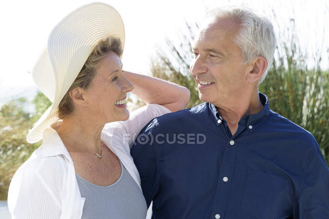 Щаслива старша пара посміхається, стоячи в саду і дивлячись один на одного — стокове фото