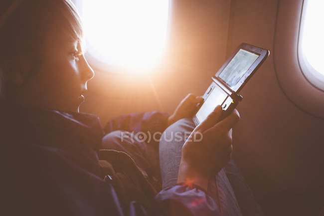 Мальчик играет в карманную видеоигру в самолете — стоковое фото