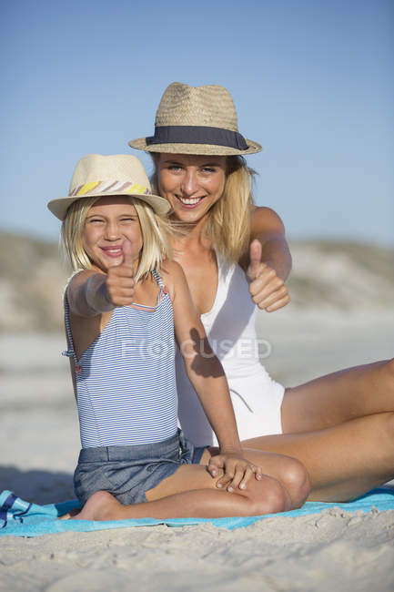 Портрет улыбающейся матери и дочери, жестикулирующих на пляже — стоковое фото
