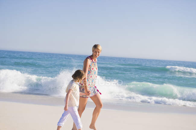 Mulher andando na praia com sua filha — Fotografia de Stock