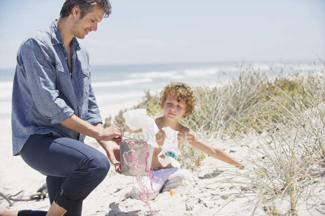 Metà uomo adulto e suo figlio la pulizia della spiaggia — Foto stock