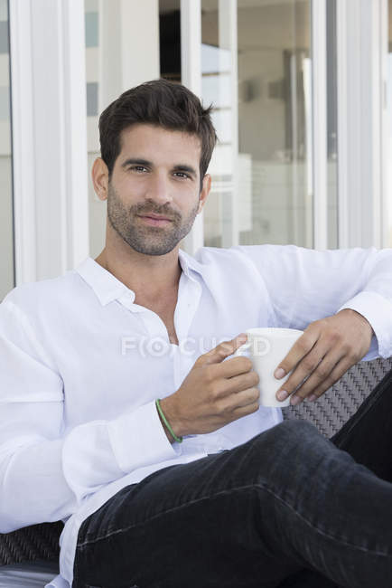 Портрет щасливого чоловіка, насолоджуючись чашкою кави на дивані вдома — стокове фото