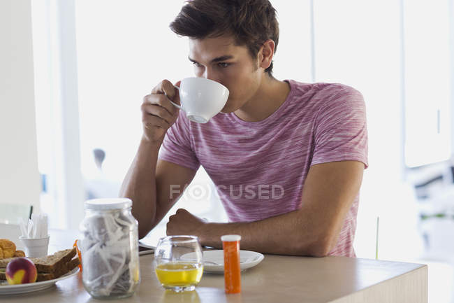 Крупный план молодого человека, пьющего кофе дома — стоковое фото