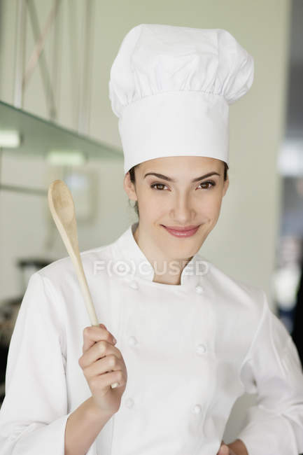 Portrait of happy female chef holding a wooden spoon — Stock Photo