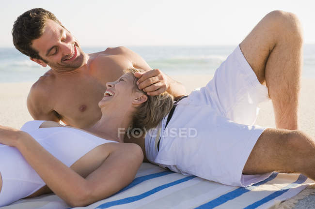 Relaxed laughing couple resting on sandy beach — Stock Photo