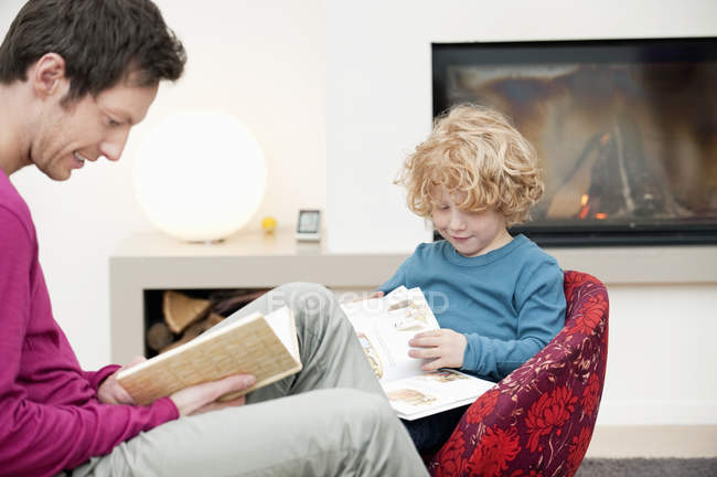 Homem e filho lendo livros em casa — Fotografia de Stock