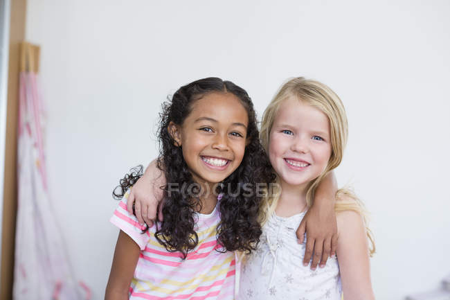 Портрет маленьких дівчаток, посміхаючись і обійматися на білому фоні — стокове фото