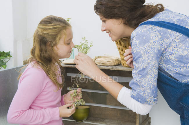 Женщина держит растение со своей дочерью, нюхает его. — стоковое фото
