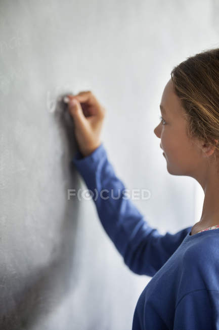 Close-up de adolescente escrevendo no quadro negro em uma sala de aula — Fotografia de Stock