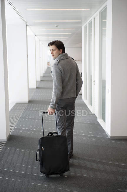 Бізнесмен несе багаж в коридорі і дивиться через плече — стокове фото