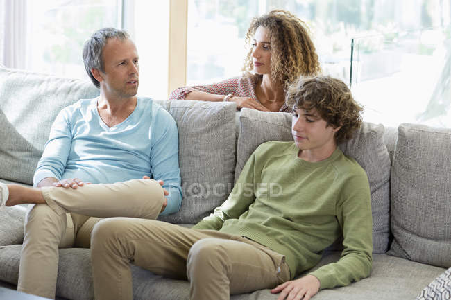 Счастливая семья разговаривает на диване в гостиной дома — стоковое фото