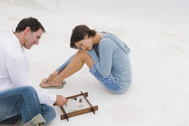 Sonriente pareja jugando con sandbox juntos - foto de stock