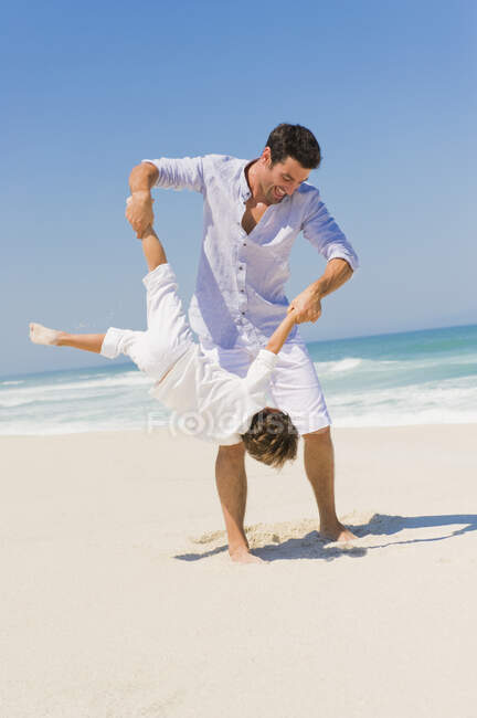Homem brincando com seu filho na praia — Fotografia de Stock