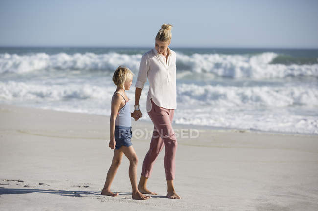 Femme détendue avec fille marchant sur la plage de sable — Photo de stock