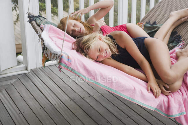 Two girls lying on a porch swing — Stock Photo