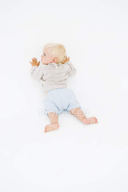 Loira menino rastejando no fundo branco — Fotografia de Stock